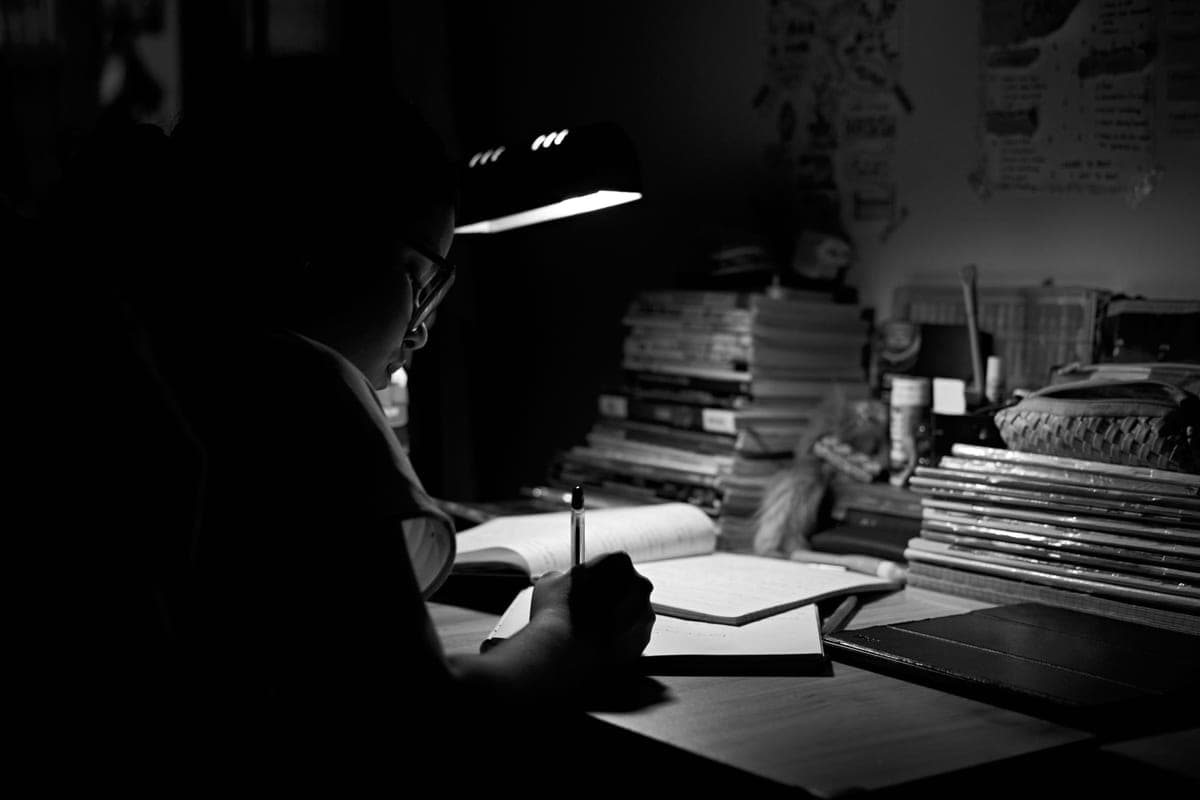 A writing desk with a notebook, a pen and a lamp