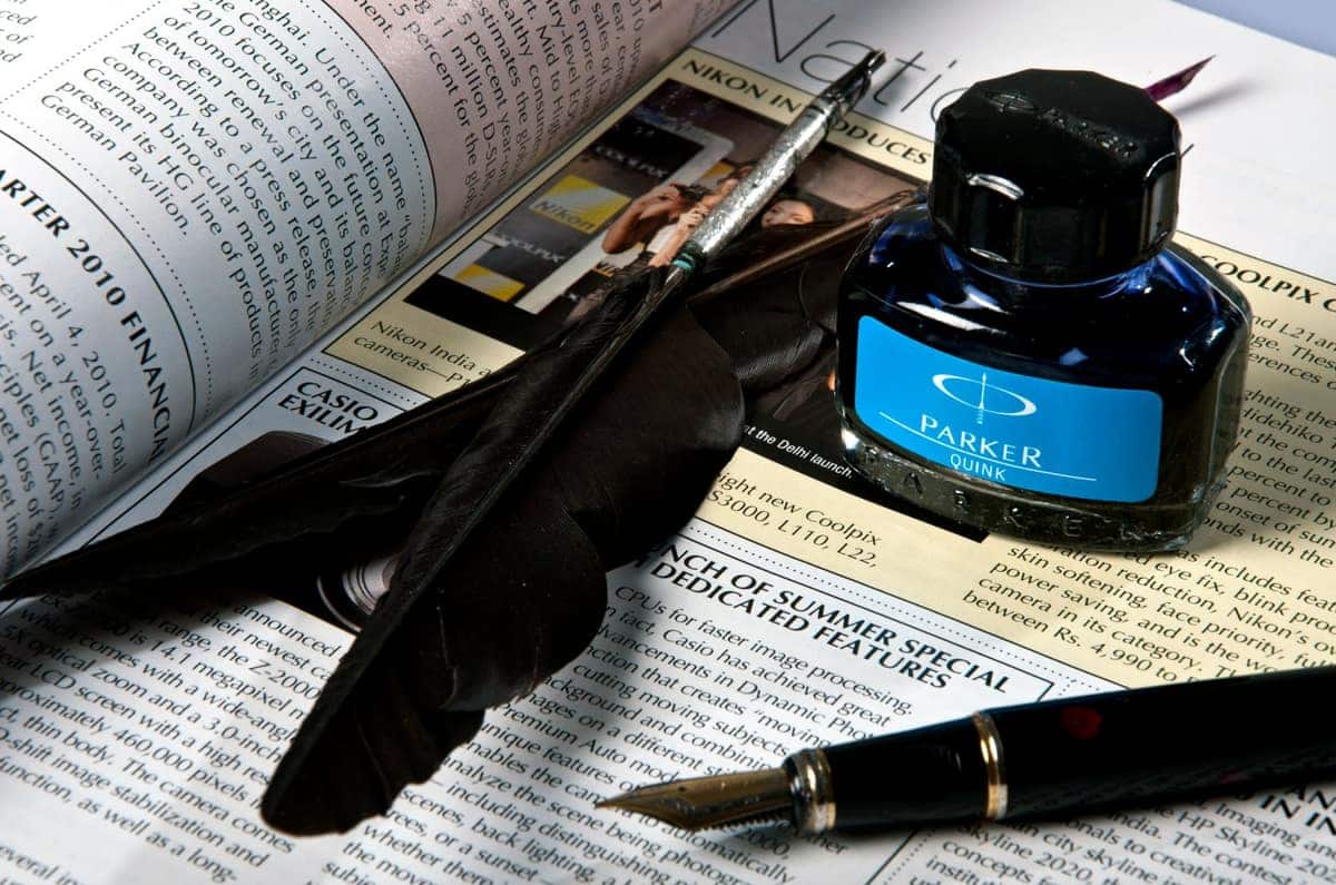 A bottle of black fountain pen ink beside a written page