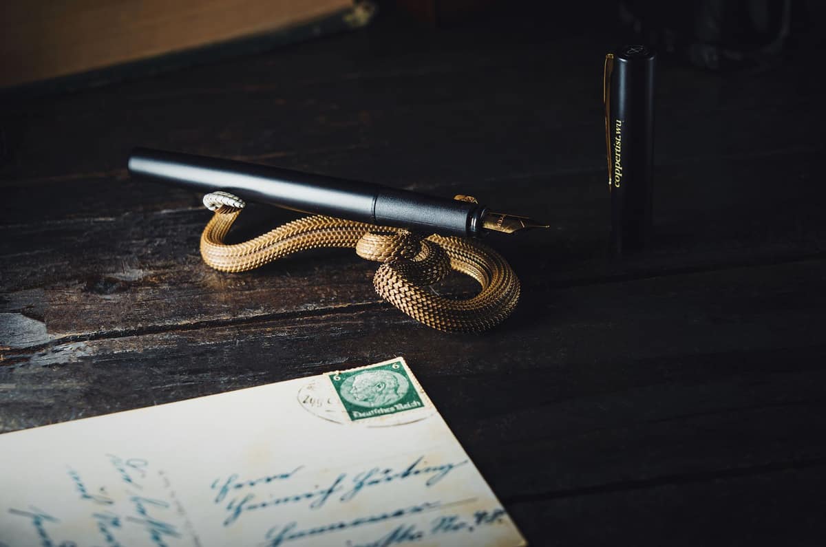 Several inexpensive fountain pens laid out on a wooden desk