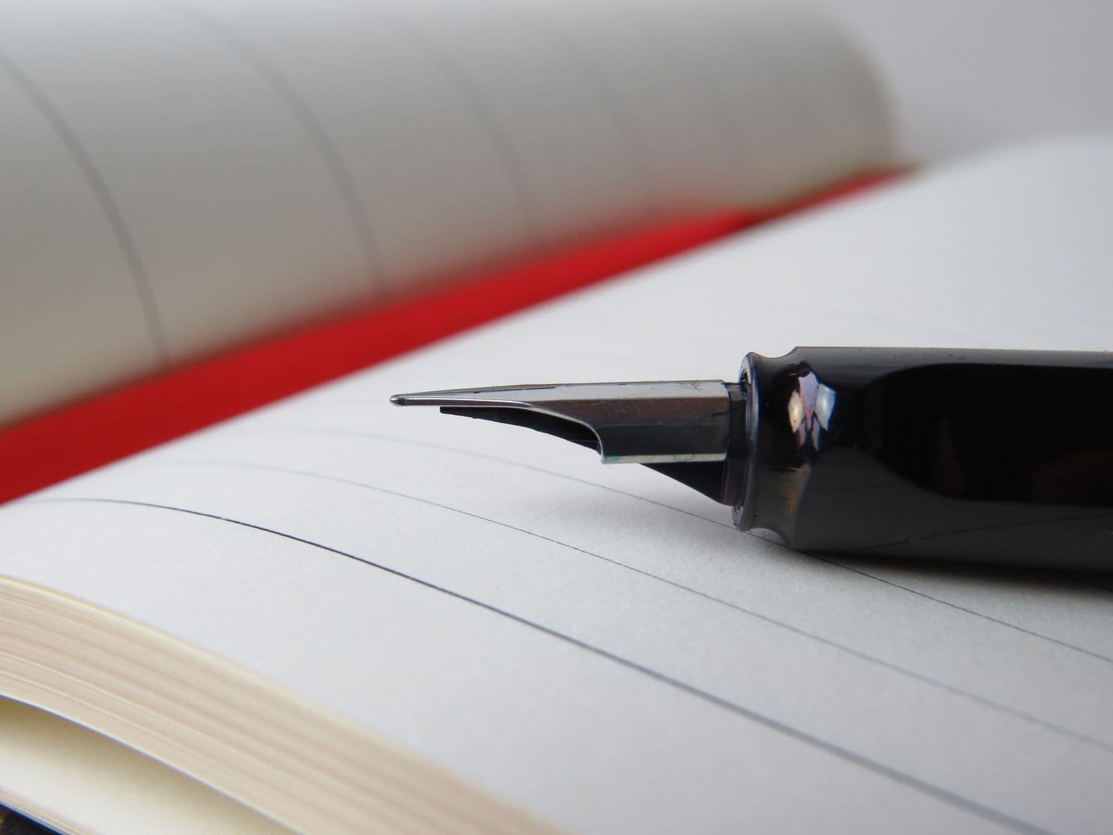 A fountain pen resting on an open lined notebook