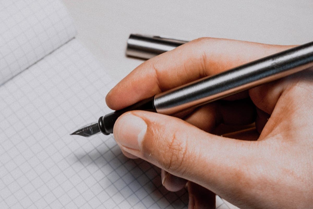 A hand holding a fountain pen while writing