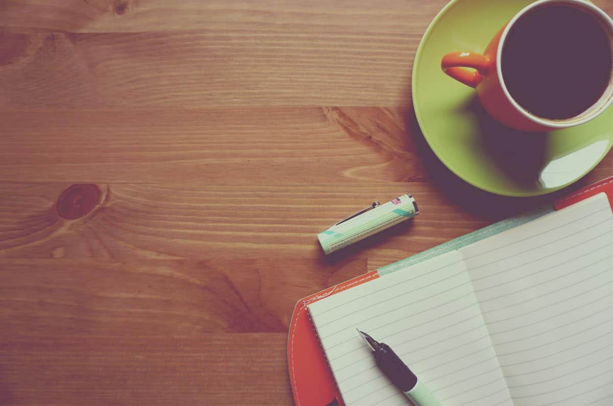 A plain notebook and fountain pen on a wooden desk