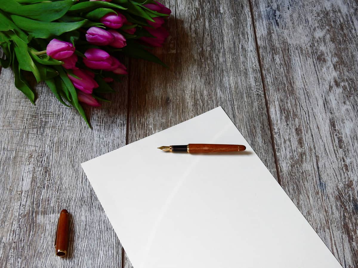 A fountain pen and notebook arranged on a plain desk