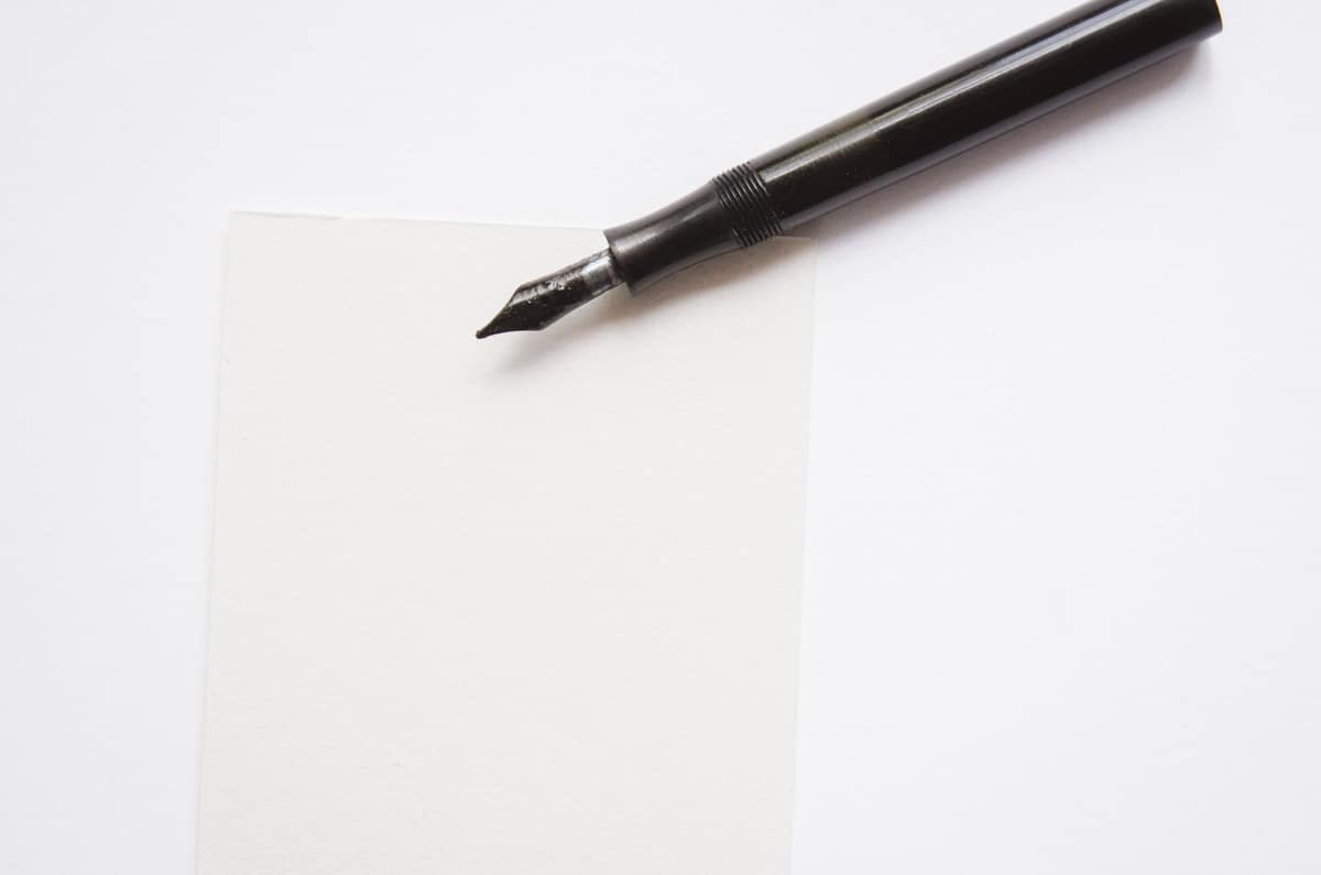A slim fountain pen on a sheet of white paper