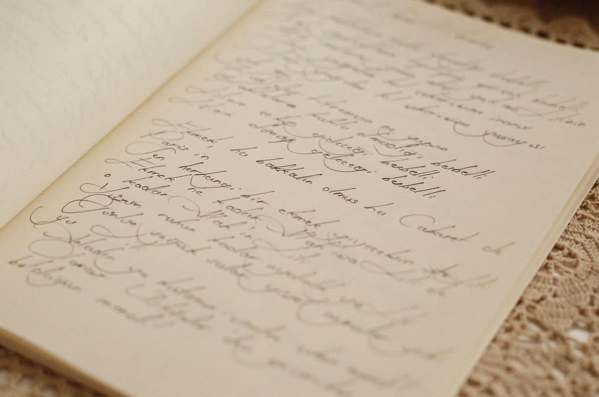 An open notebook covered in handwriting beside a fountain pen