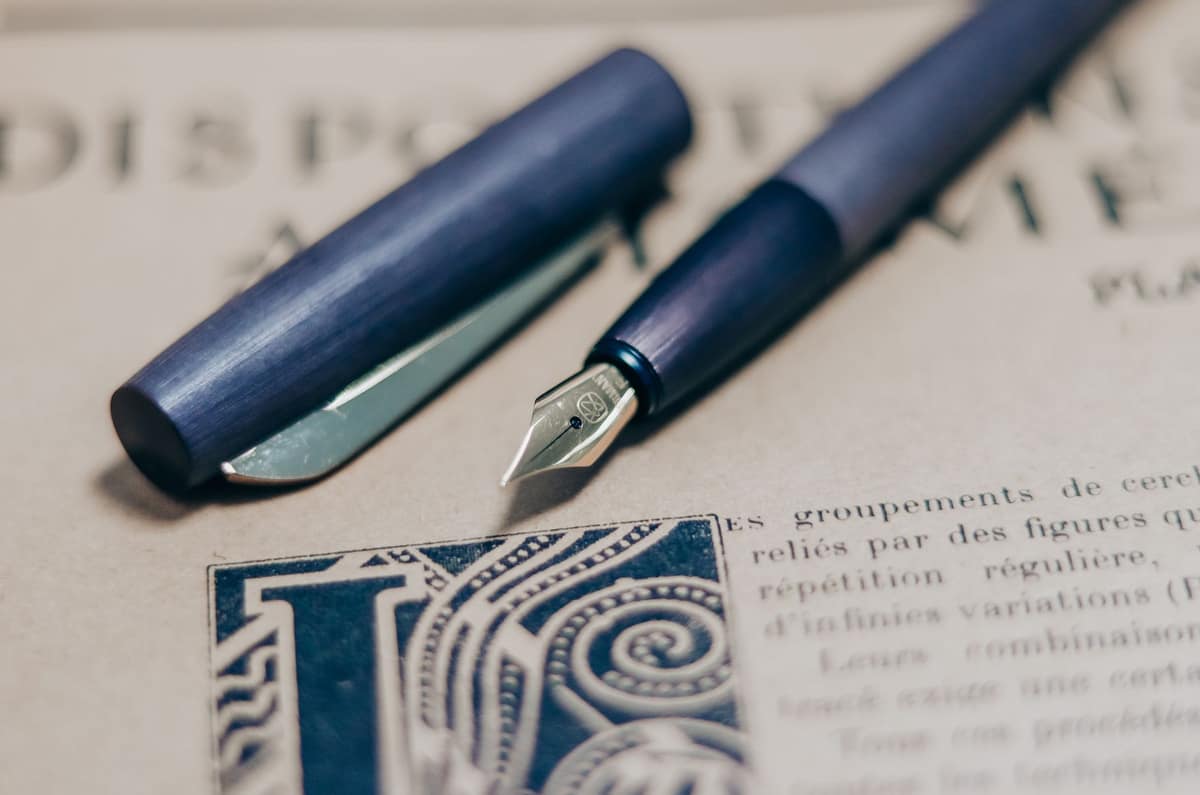 Two fountain pens lying side by side on a desk