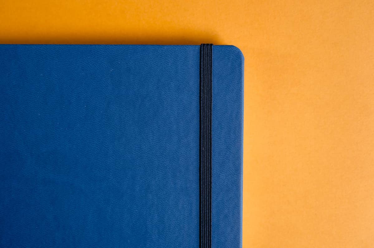 A black hardcover notebook closed with an elastic band on a desk