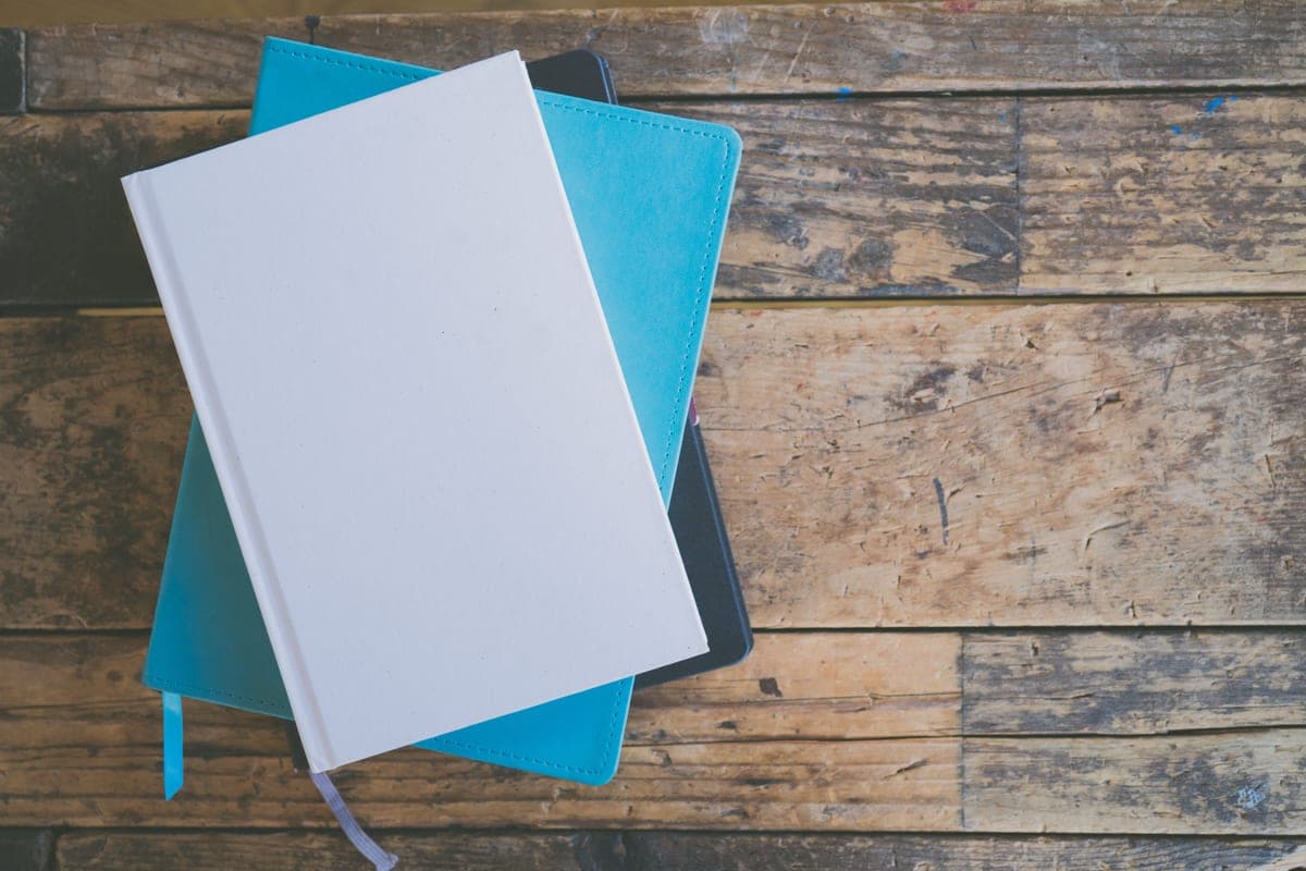 Two journals stacked on a wooden desk