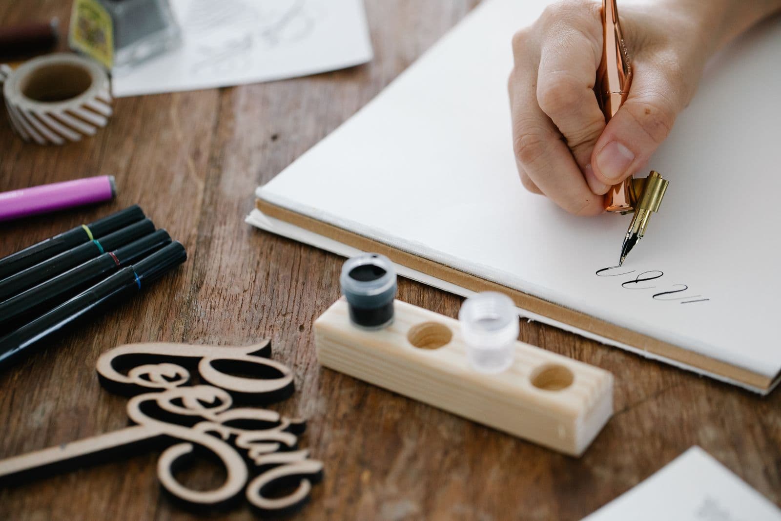 Close-up of hand lettering made with a broad pen and ink on a wooden table