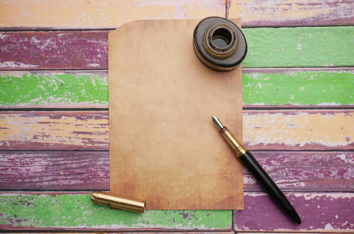 A fountain pen beside an open bottle of ink