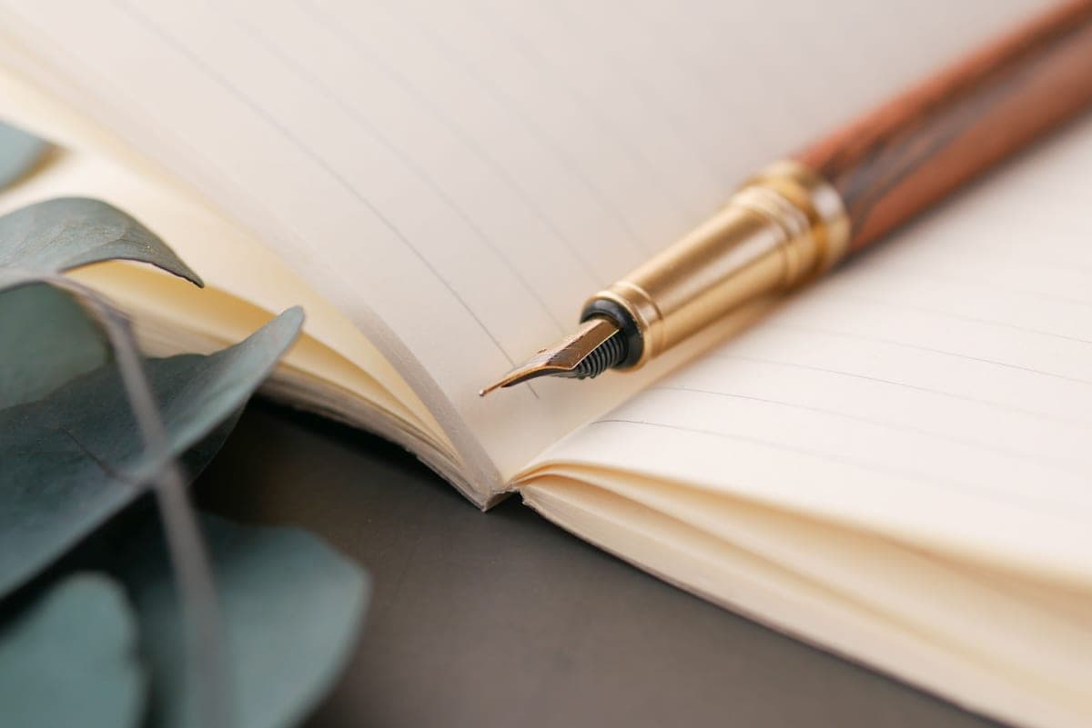 Two fountain pens laid on an open notebook