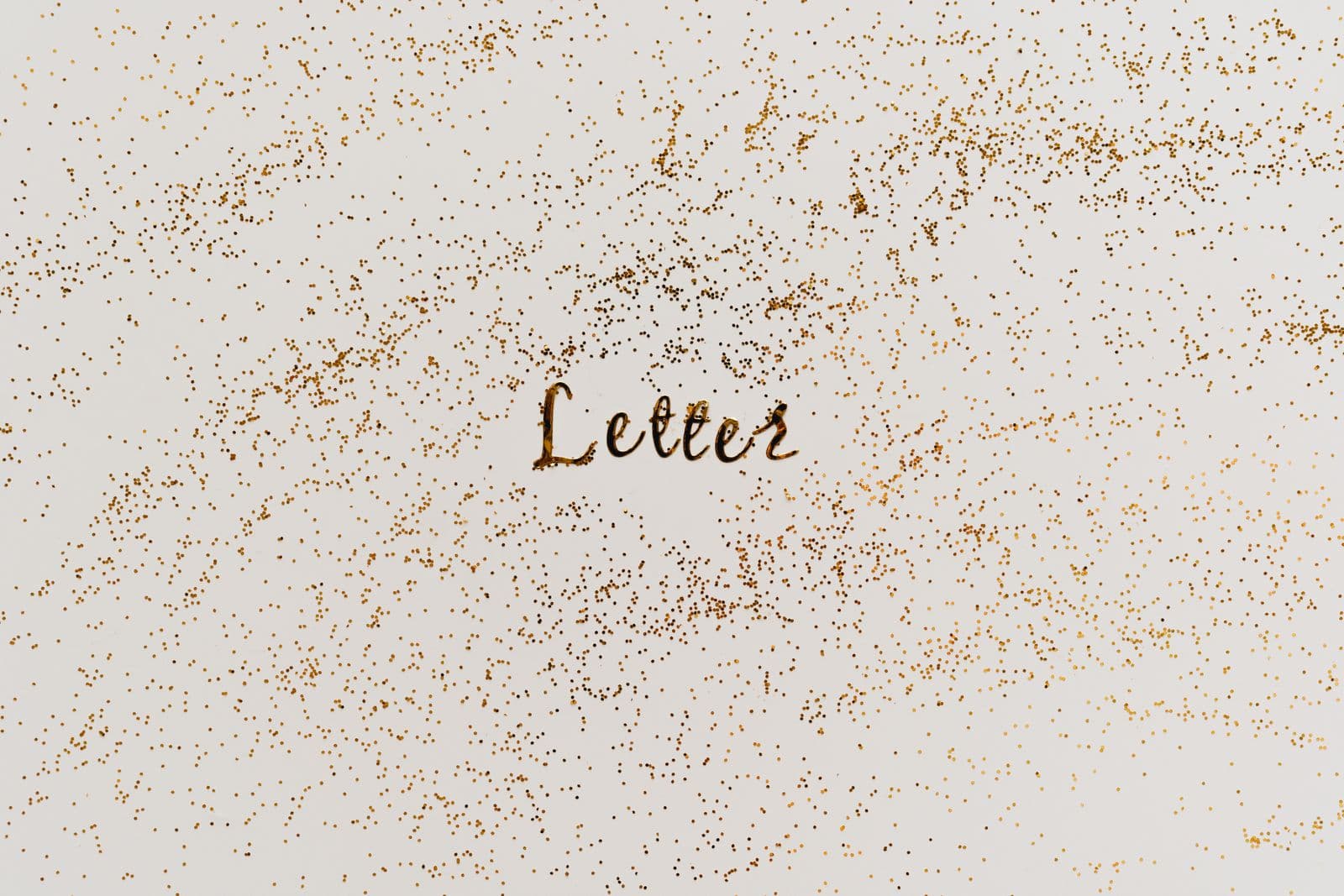 The word Letter written on white paper surrounded by scattered gold glitter