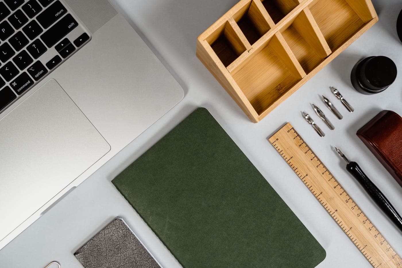 A fountain pen, an ink bottle and an open notebook laid out on a desk