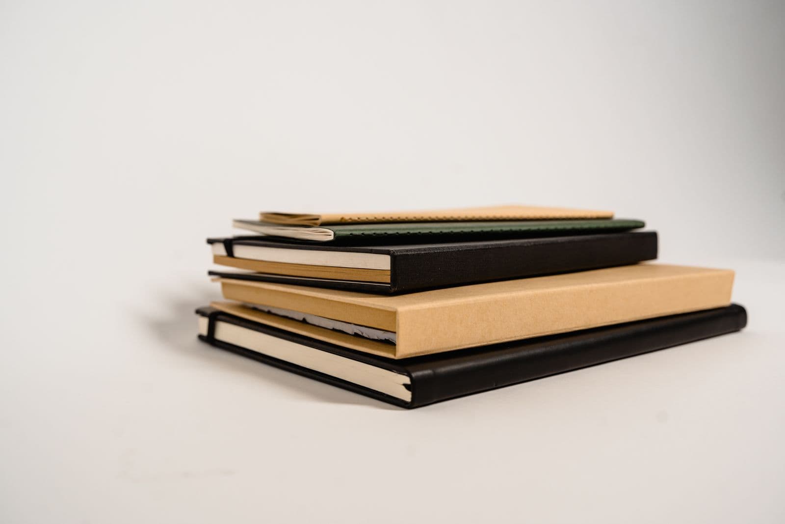 A stack of notebooks of different colors and textures on a white background