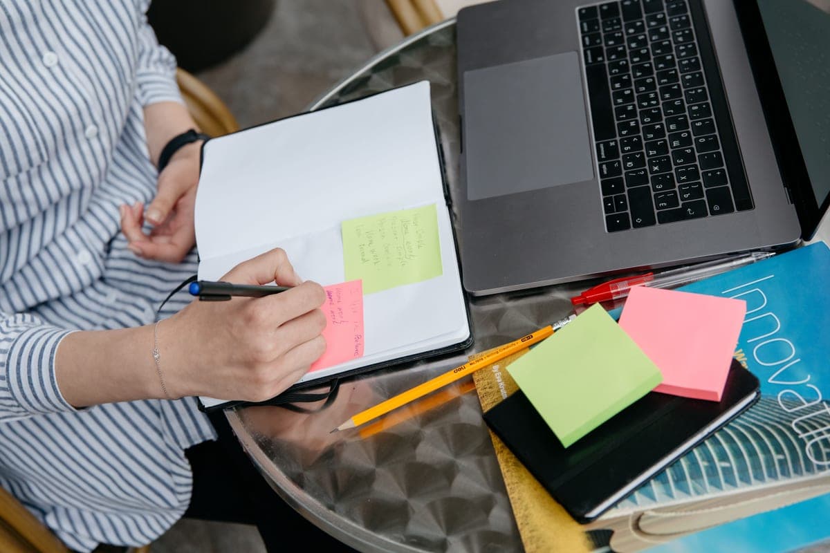 A person considering a notebook and pen